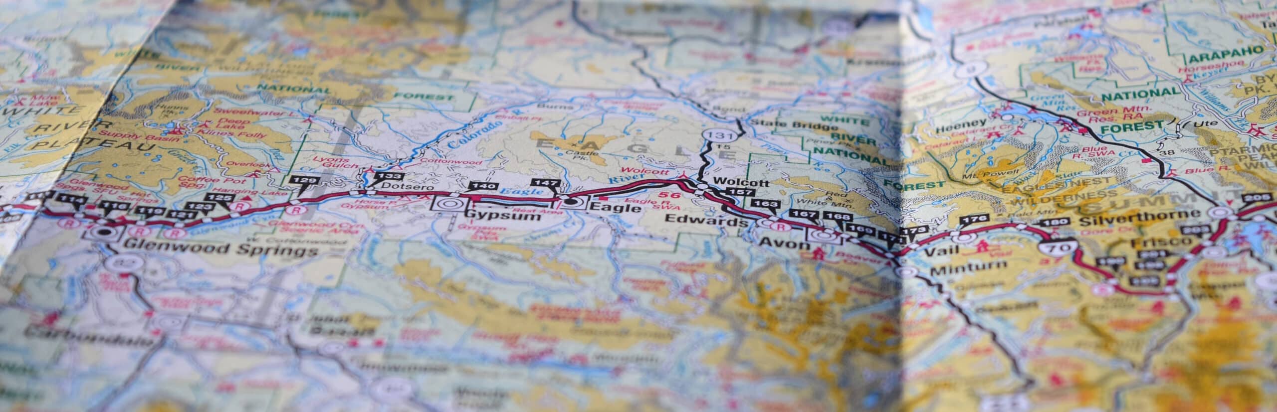 A close-up of a detailed geographic map showing a section of a roadway highlighted in red. Marked locations include Glenwood Springs, Gypsum, Eagle, Edwards, Avon, and Vail. Surrounding areas include National Forests and other towns. The map has visible folds.